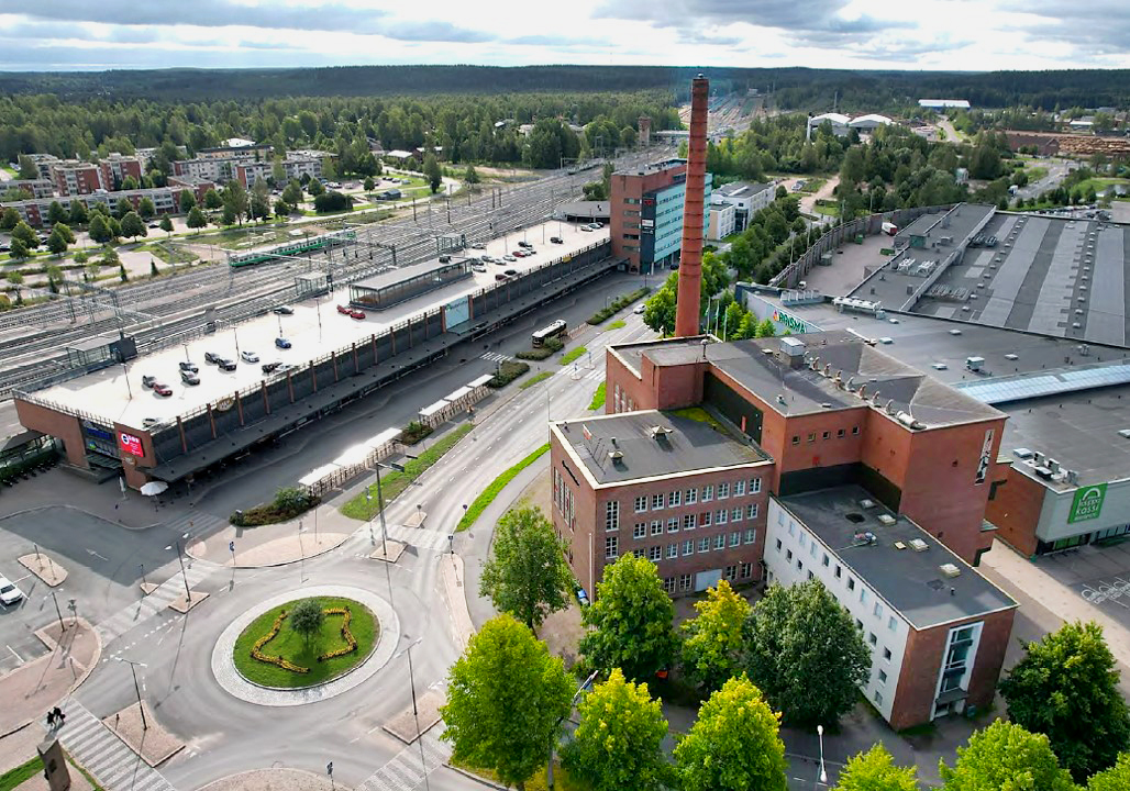 Punatiilinen voimalarakennus kuvassa etualalla, kuvassa vasemmalla Riihimäen juna-asema ja rautatie.